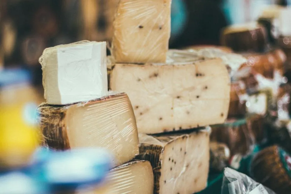 Stacked wheels and wedges of aged cheese on a market stall